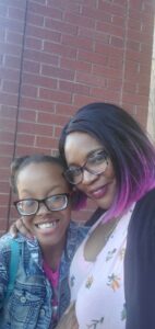 Dr Z black woman with black hair and pink ends wearing glasses smiling and standing next to her daughter young black girl with glasses smiling